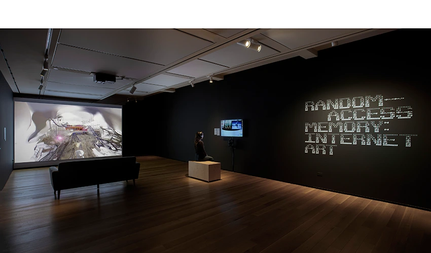 gallery of random access memory internet art show with a view of the wall projection and the couch in front of it and a mounted monitor with a bench